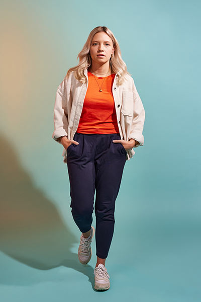 Eine junge Frau mit Shirt und Jacke läuft dynamisch in Richtung Kamera.